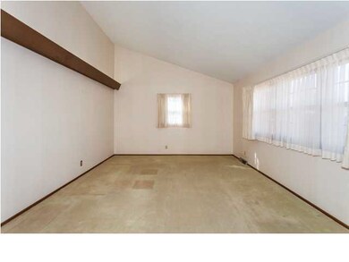 Living room has angled ceiling. Under carpet are l