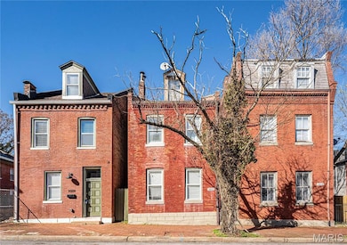 View of front of home featuring brick siding and a chimney