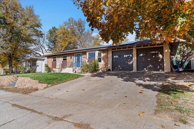 View of front facade featuring driveway, roof mounted solar panels, a garage, a front lawn, and brick siding