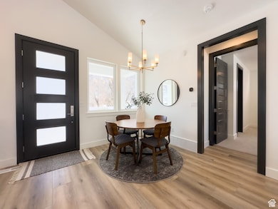 Dining space featuring vaulted ceiling, light wood finished floors, and a chandelier