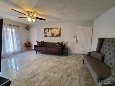 Living room featuring ceiling fan and a textured ceiling