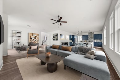 Living room with plenty of natural light, a ceiling fan, dark wood-type flooring, and a chandelier