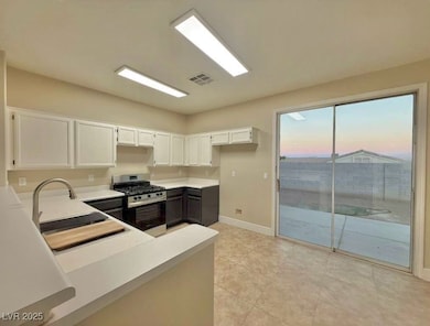 Kitchen featuring white cabinetry, stainless steel gas stove, light countertops, and light tile patterned floors
