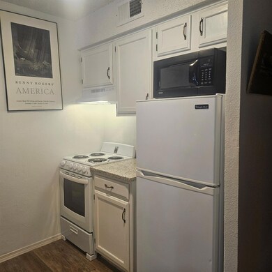 Kitchen with visible vents, white appliances, dar
