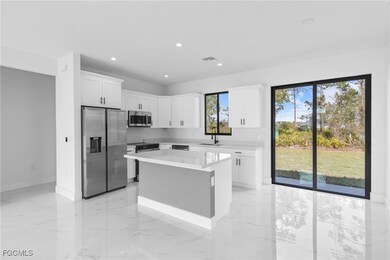 Kitchen featuring appliances with stainless steel finishes, light marble finish floors, white cabinets, a center island, and recessed lighting