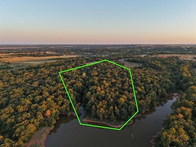 Aerial view at dusk of a water view, a wooded view, and property boundaries highlighted