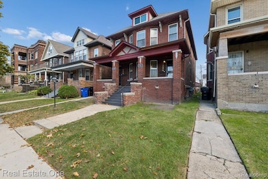 View of front facade with brick siding, a front lawn, and a porch