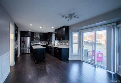 Kitchen featuring tasteful backsplash, appliances with stainless steel finishes, dark cabinetry, a center island, and dark wood-type flooring