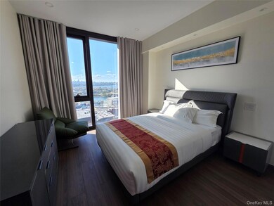 Bedroom with expansive windows, dark wood finished floors, a water view, and a view of city