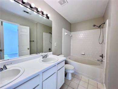 Full bathroom featuring double vanity, light tile patterned floors, and shower / bath combination