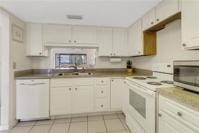 Kitchen with white appliances, light tile patterne