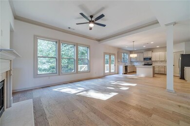Unfurnished living room featuring light wood finished floors, a high end fireplace, a ceiling fan, and crown molding