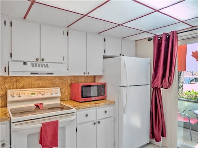 Kitchen with white appliances, white cabinets, light countertops, extractor fan, and tasteful backsplash