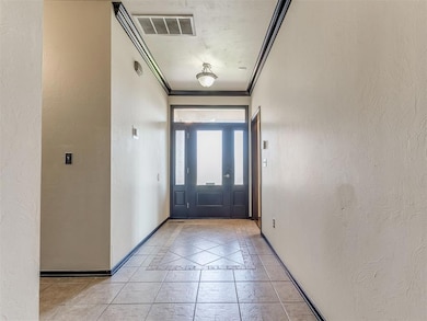 Entrance foyer featuring crown molding, a textured wall, light tile patterned flooring, and inlaid floor details