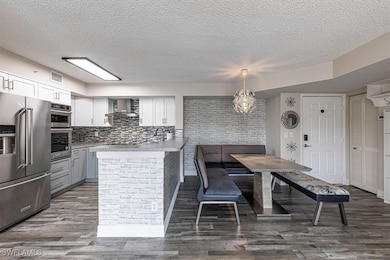 Kitchen with stainless steel appliances, a textured ceiling, dark wood-style flooring, light countertops, and gray cabinets