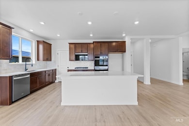 Kitchen with tasteful backsplash, a center island, appliances with stainless steel finishes, light wood-type flooring, and recessed lighting