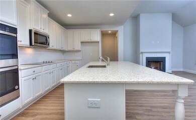 Kitchen with a sink, appliances with stainless steel finishes, light wood-style flooring, white cabinetry, and a kitchen island with sink