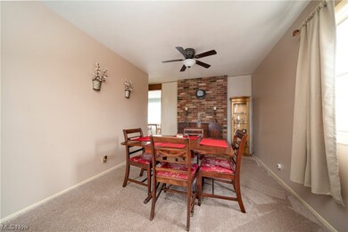Carpeted dining room with brick wall and ceiling fan