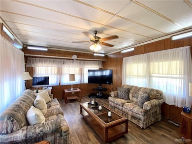 Living area featuring wooden walls, ceiling fan, and dark wood-style floors
