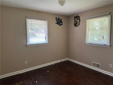 Spare room featuring dark wood-style flooring and baseboards