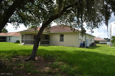 Back of house with stucco siding, a yard, and a su