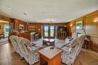 Living area with a textured ceiling, wood walls, and french doors