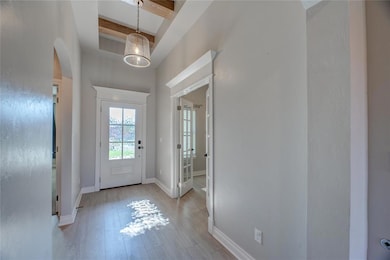 Entryway with wood finished floors, beam ceiling, arched walkways, and a towering ceiling