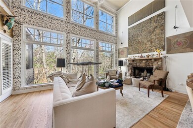 Living room with a high ceiling, wood finished floors, a fireplace, baseboards, and ornamental molding