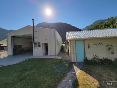 View of front of property with a mountain view, a garage, an outbuilding, a front lawn, and a metal roof