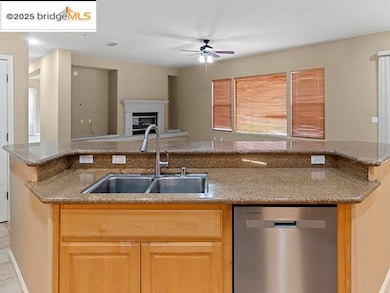 Kitchen with dishwasher, light brown cabinetry, ceiling fan, open floor plan, and dark stone countertops
