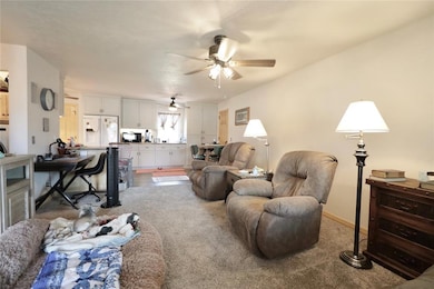 Living area with light carpet and ceiling fan
