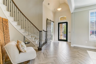 Foyer featuring stairs, a barn door, high vaulted ceiling, and ornamental molding