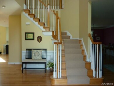 Two story foyer has gleaming hardwood floors and e