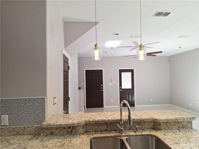 Kitchen featuring ceiling fan, hanging light fixtures, tile patterned floors, light stone countertops, and sink