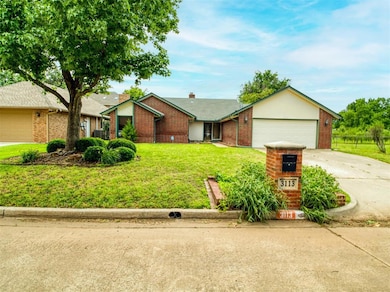 Ranch-style home with brick siding, concrete driveway, an attached garage, a front yard, and a chimney