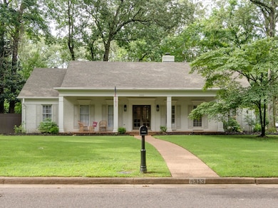 View of front of property featuring a porch, brick siding, roof with shingles, and a chimney
