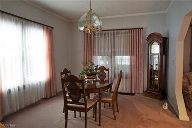 Carpeted dining area featuring plenty of natural light, ornamental molding, and a notable chandelier