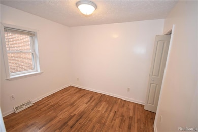 Empty room with wood-type flooring and a textured ceiling