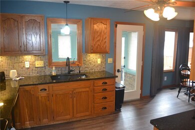 Kitchen also has tile backsplash with undermount cabinet lighting and looks out to sunroom.