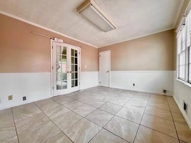 Unfurnished room featuring a textured ceiling, french doors, and crown molding