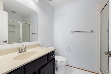 Bathroom featuring toilet, a stall shower, baseboa