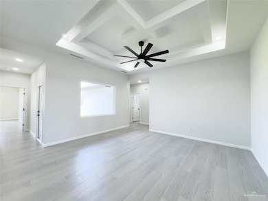 Unfurnished room with ceiling fan, light wood-type flooring, a raised ceiling, and coffered ceiling
