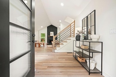 Foyer featuring luxury vinyl plank flooring, stairway, a stone fireplace, recessed lighting, and high vaulted ceiling.