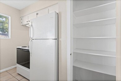 Kitchen featuring white appliances, light tile patterned flooring, and white cabinets