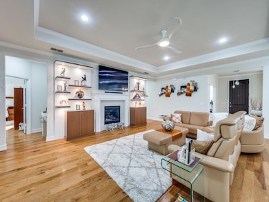 Living room featuring a tray ceiling, light hardwo
