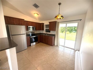 Kitchen featuring tasteful backsplash, stainless steel appliances, pendant lighting, vaulted ceiling, and light tile patterned floors