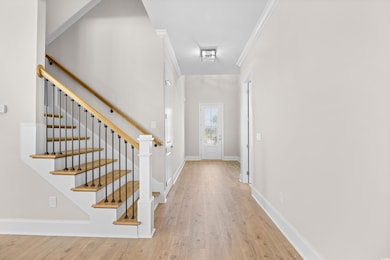 Foyer entrance featuring wood finished floors, stairway, and ornamental molding