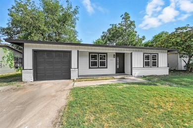 Single story home with brick siding, board and batten siding, driveway, an attached garage, and a front yard
