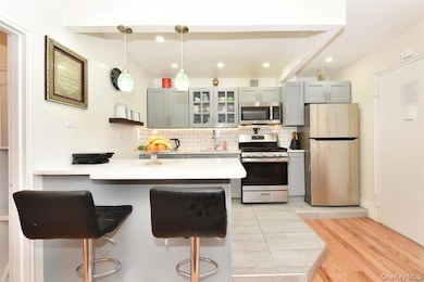 Kitchen with a peninsula, tasteful backsplash, stainless steel appliances, a kitchen bar, and glass insert cabinets