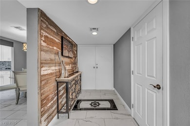Corridor with light marble finish floors and recessed lighting